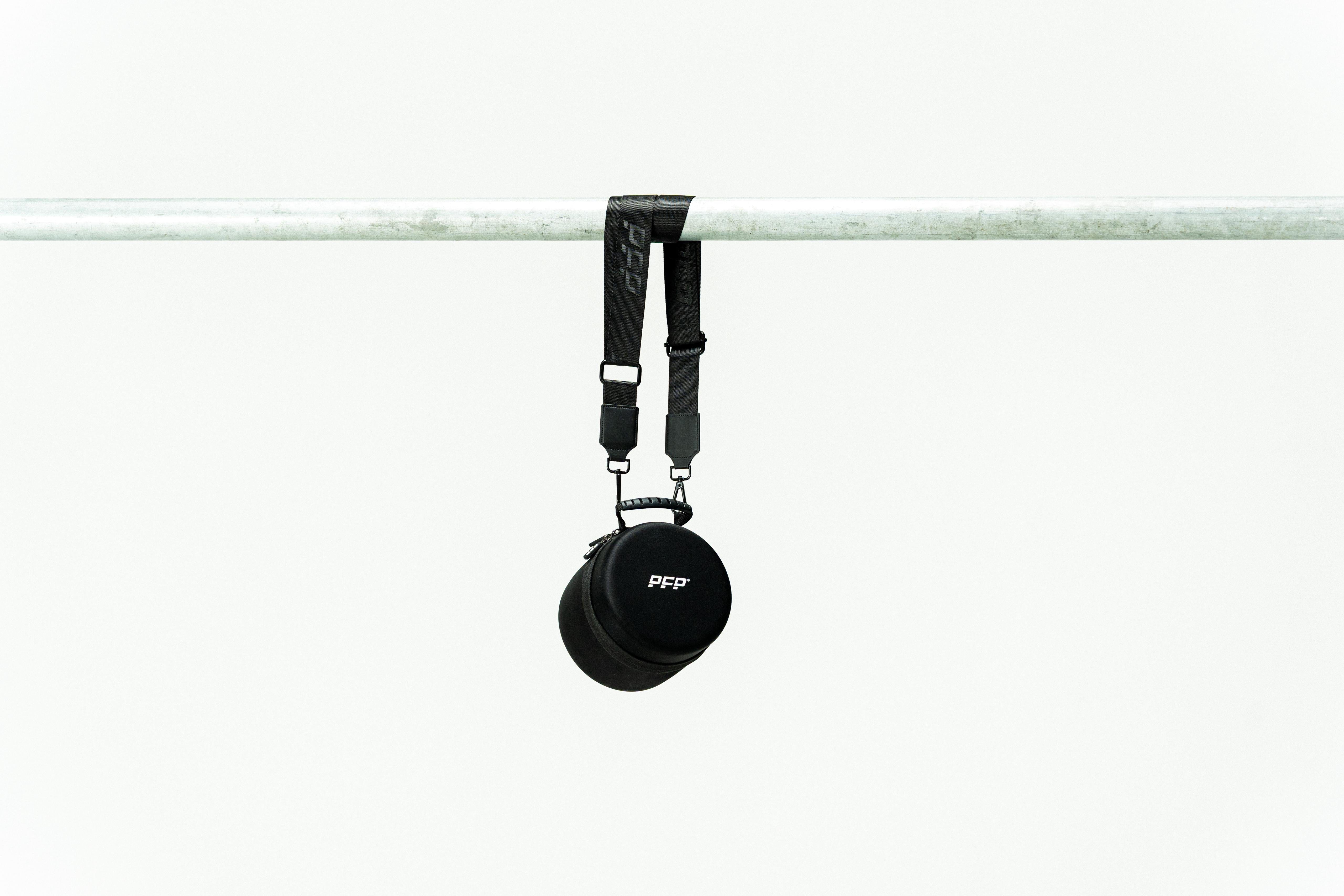 Black Packed for Performance brand bag with strap hanging on a white background